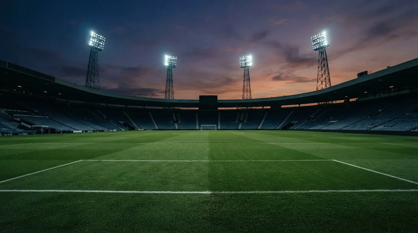 Een leeg voetbalstadion met lichtmasten bij schemering