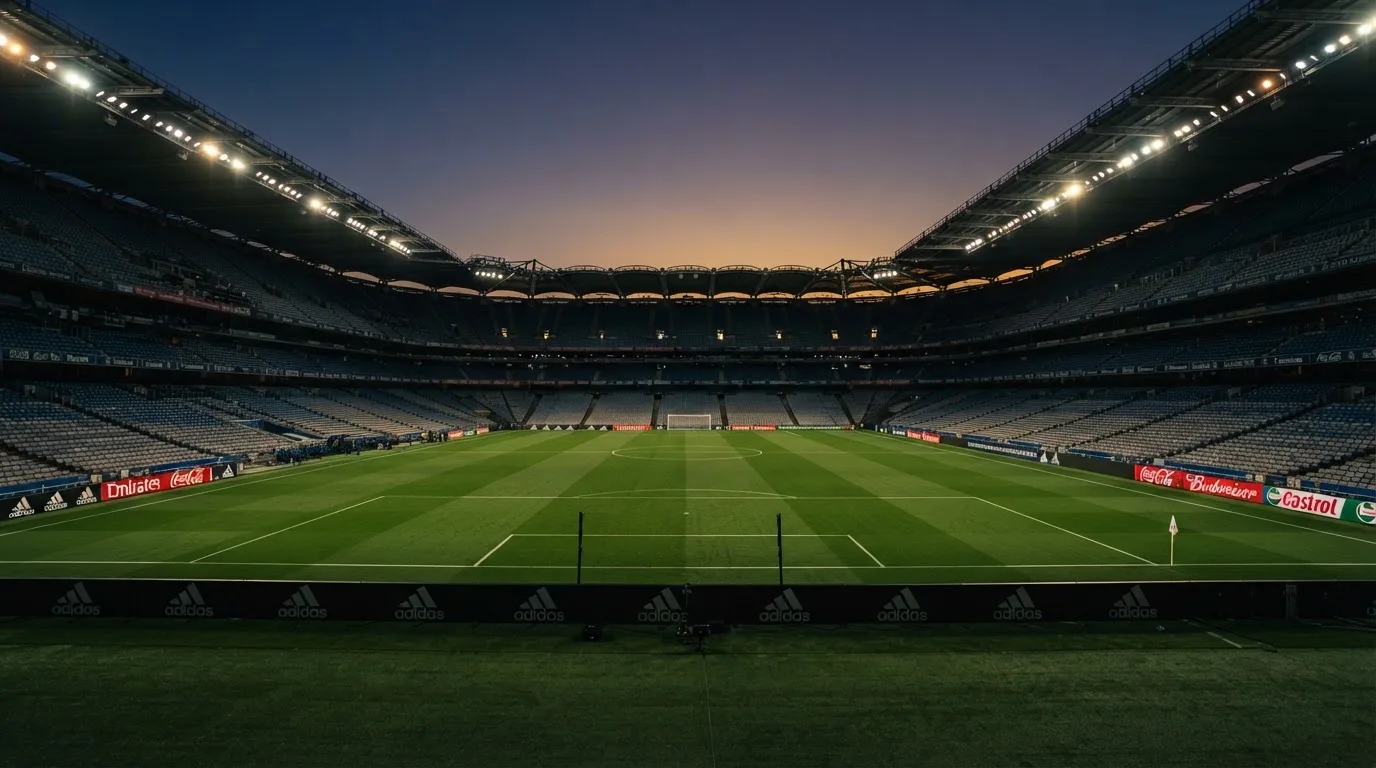 Een leeg voetbalstadion met lichtmasten bij schemering