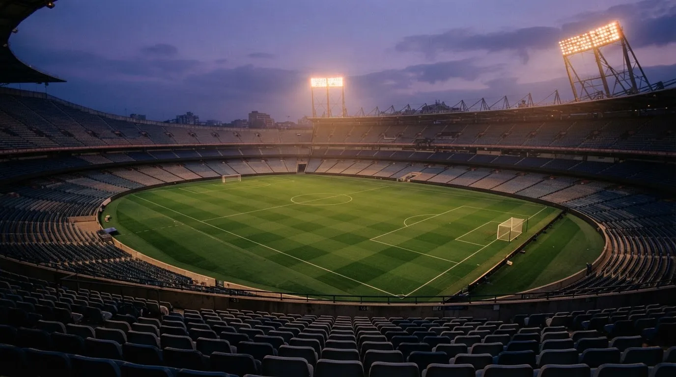 Een leeg voetbalstadion met lichtmasten bij schemering