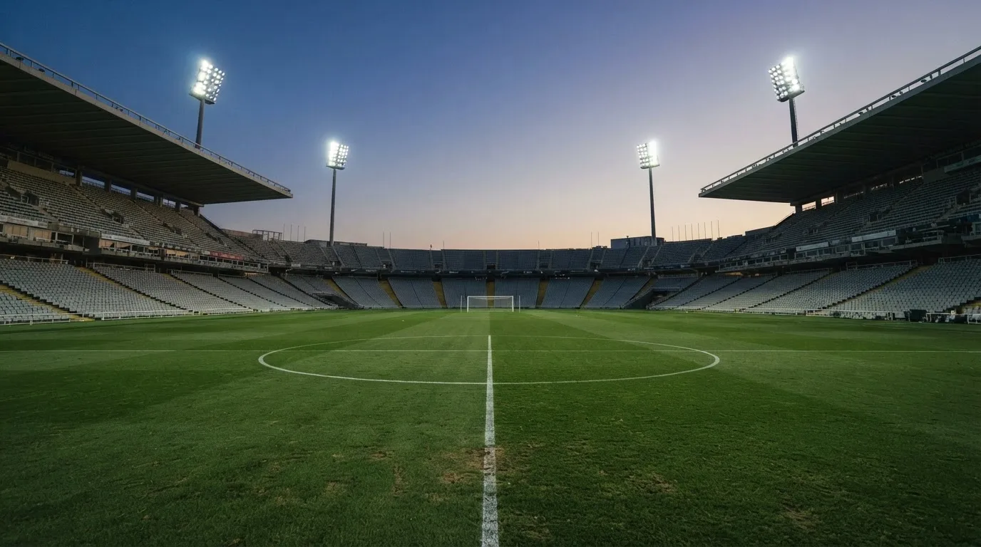Een leeg voetbalstadion met lichtmasten bij schemering