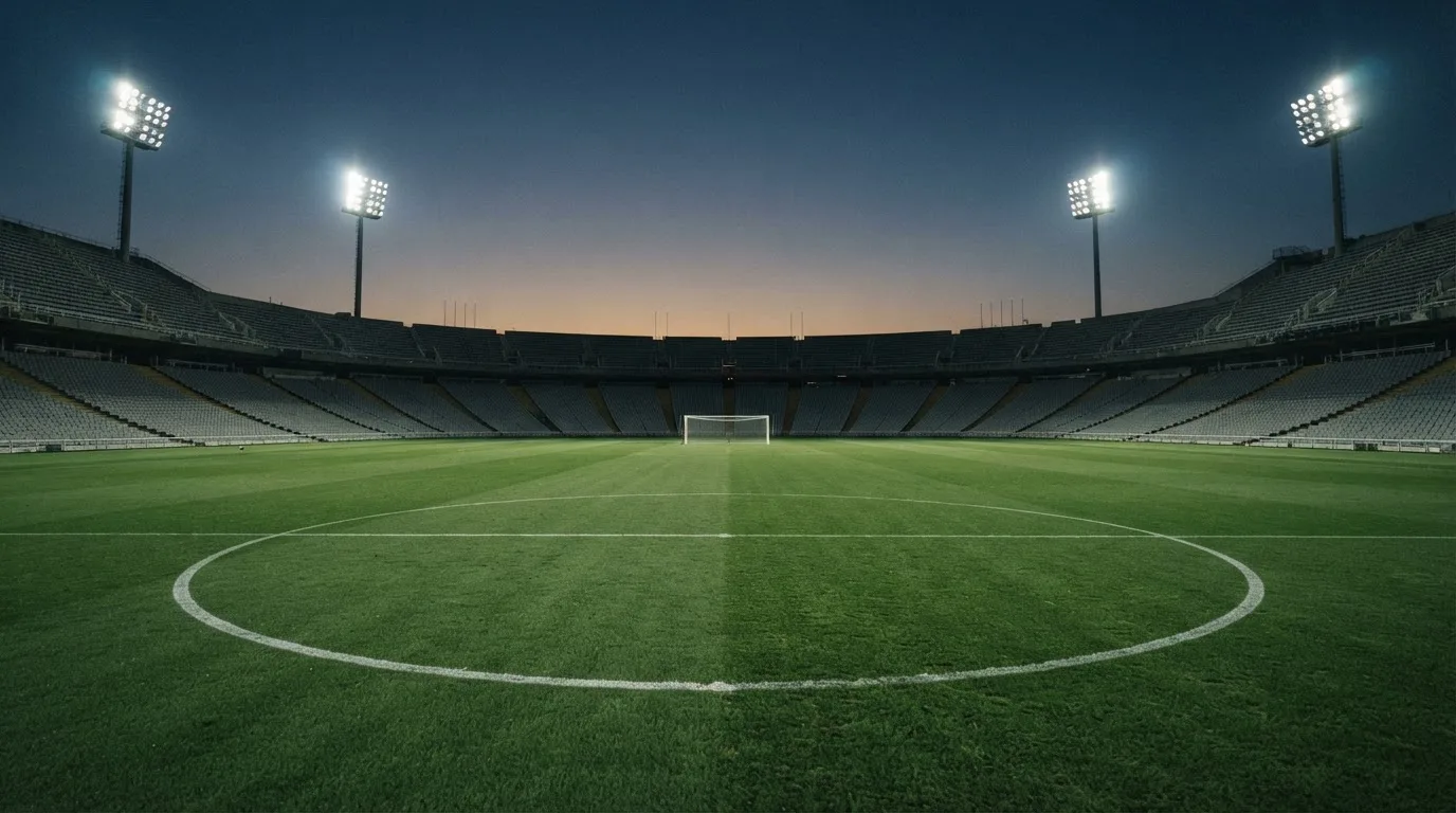 Een leeg voetbalstadion met lichtmasten bij schemering