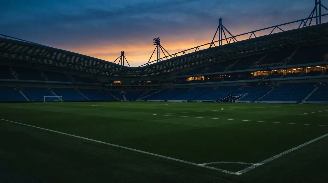 Een leeg voetbalstadion met lichtmasten bij schemering