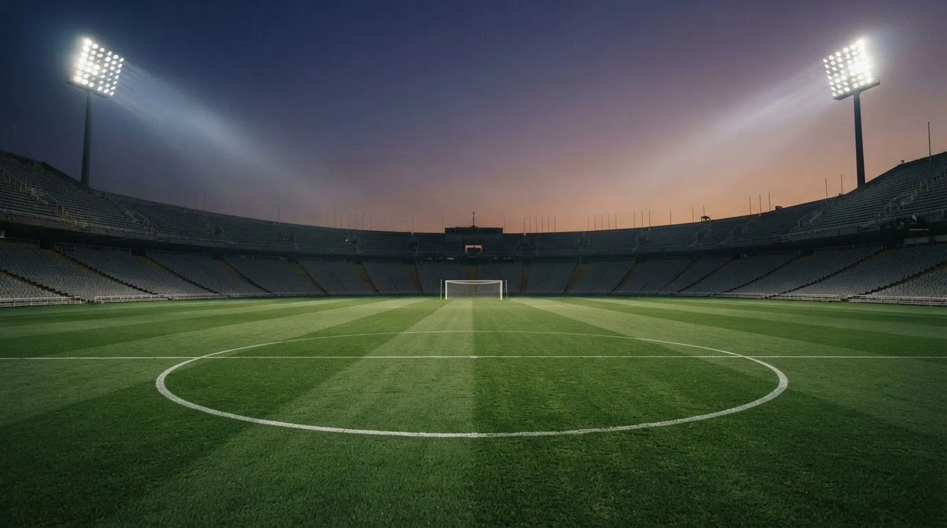 Een leeg voetbalstadion met lichtmasten bij schemering
