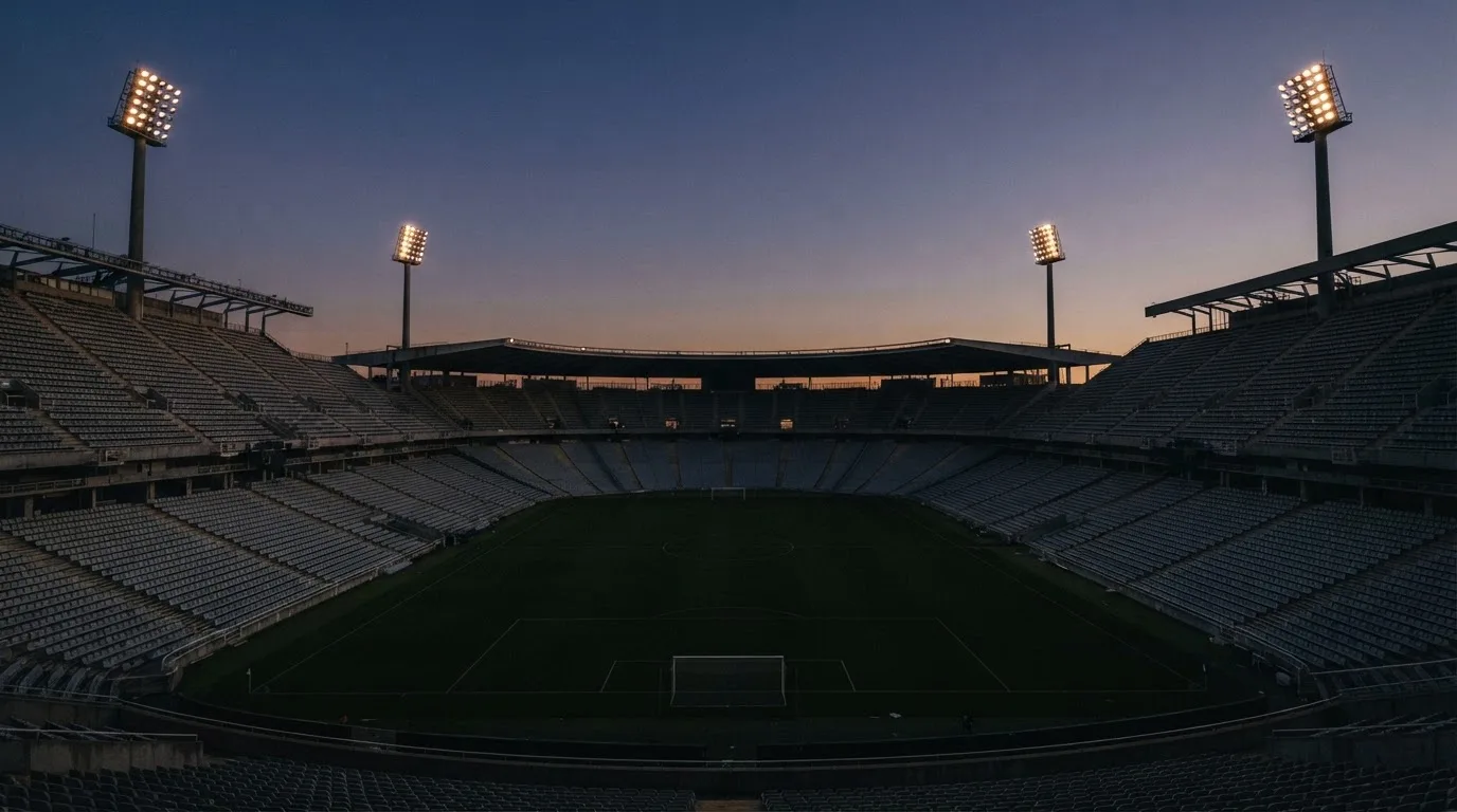 Een leeg voetbalstadion met lichtmasten bij schemering