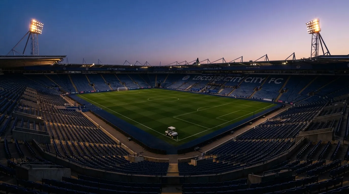 Een leeg voetbalstadion met lichtmasten bij schemering