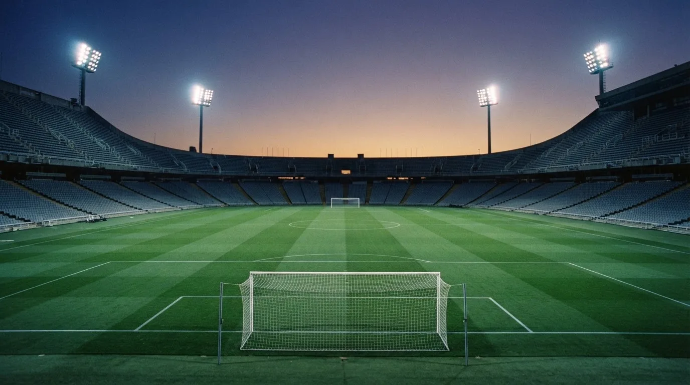 Een leeg voetbalstadion met lichtmasten bij schemering