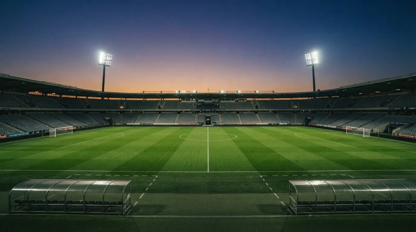 Een leeg voetbalstadion met lichtmasten bij schemering