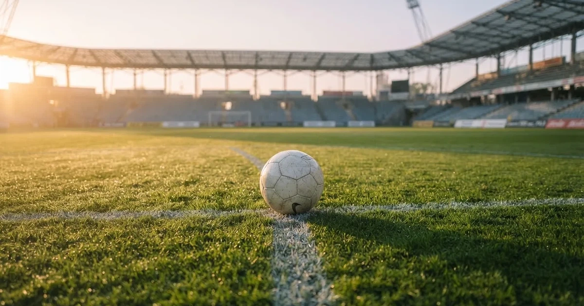Een voetbal op de middenstip van een grasveld in het ochtendlicht