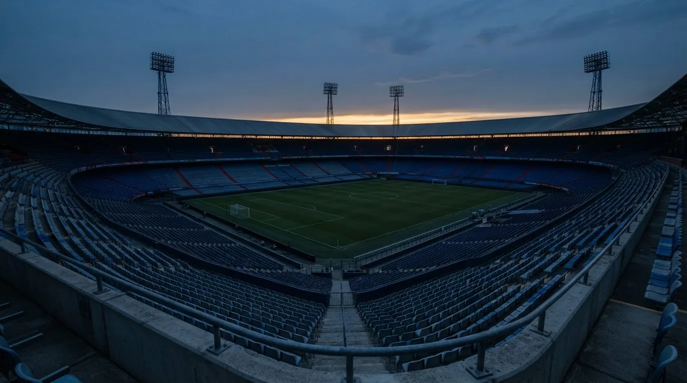 Een leeg voetbalstadion met lichtmasten bij schemering